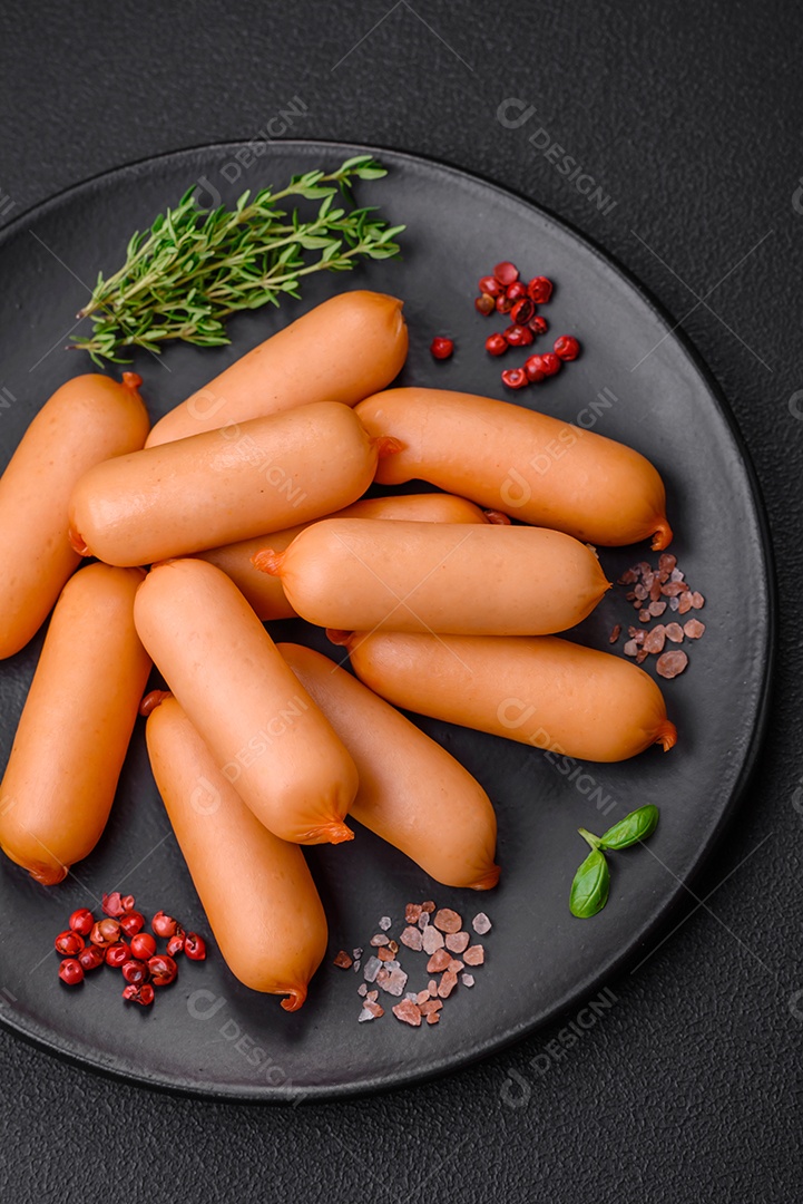 Deliciosas salsichas frescas cozidas com sal, especiarias e ervas sobre um fundo escuro de concreto