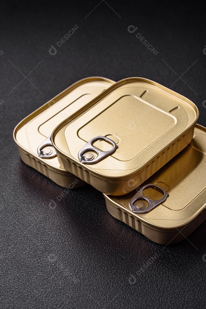 Lata retangular de estanho ou alumínio de alimentos enlatados com uma chave sobre um fundo escuro de concreto