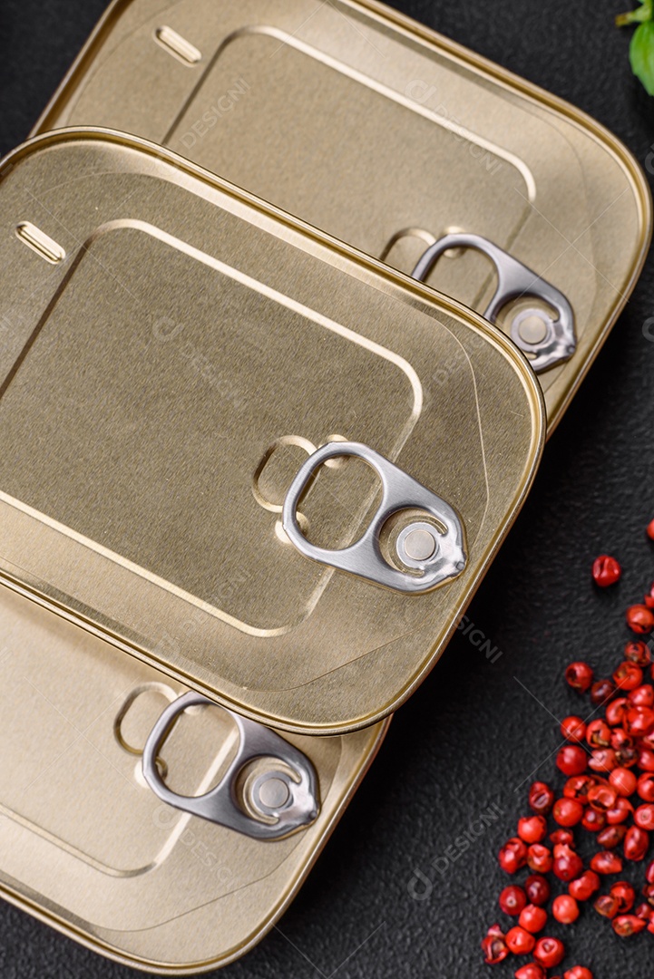 Lata retangular de estanho ou alumínio de alimentos enlatados com uma chave sobre um fundo escuro de concreto