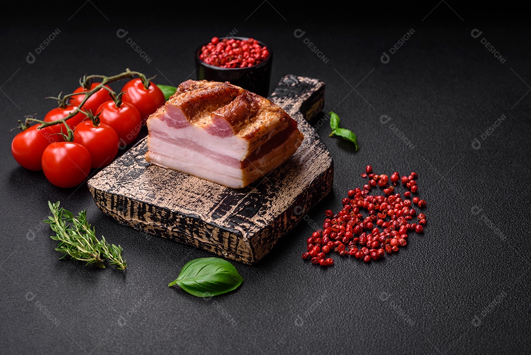 Delicioso bacon defumado com sal, especiarias e ervas sobre um fundo escuro de concreto