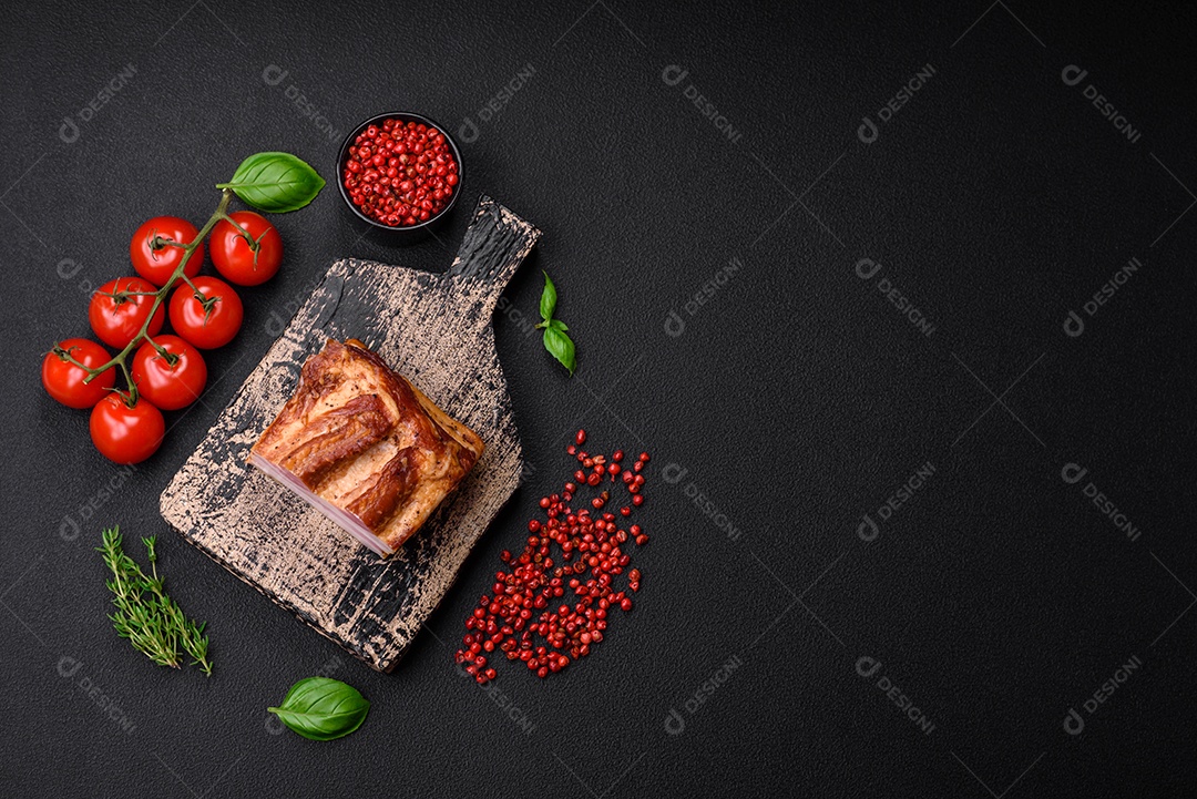 Delicioso bacon defumado com sal, especiarias e ervas sobre um fundo escuro de concreto