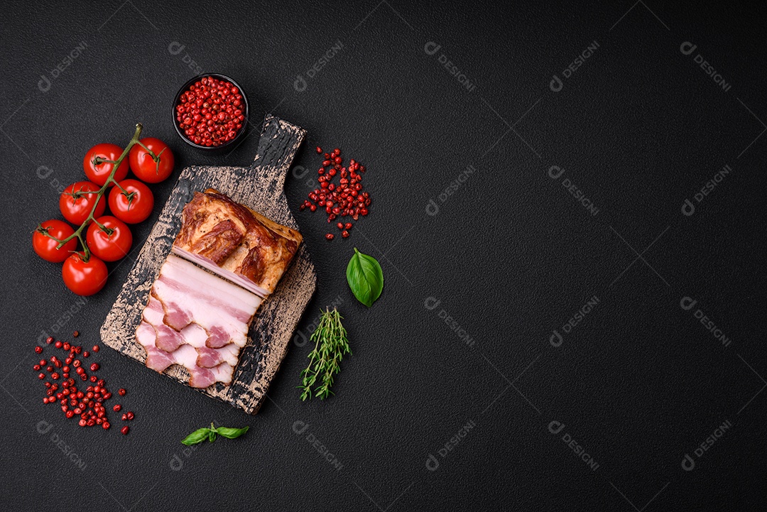 Delicioso bacon defumado com sal, especiarias e ervas sobre um fundo escuro de concreto