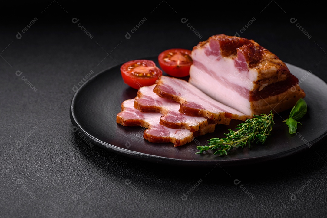 Delicioso bacon defumado com sal, especiarias e ervas sobre um fundo escuro de concreto