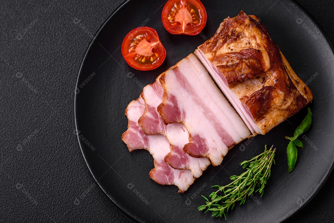Delicioso bacon defumado com sal, especiarias e ervas sobre um fundo escuro de concreto