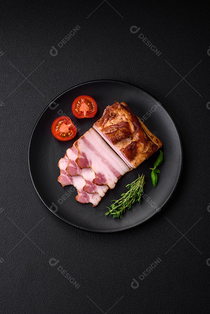 Delicioso bacon defumado com sal, especiarias e ervas sobre um fundo escuro de concreto