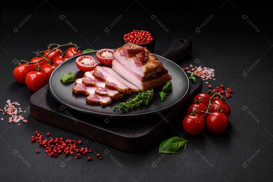 Delicioso bacon defumado com sal, especiarias e ervas sobre um fundo escuro de concreto