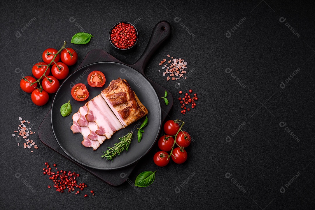 Delicioso bacon defumado com sal, especiarias e ervas sobre um fundo escuro de concreto
