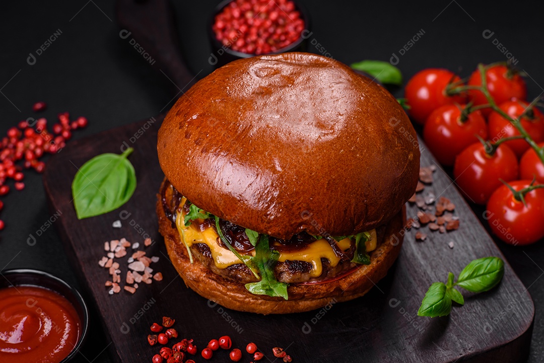 Hambúrguer com suculenta costeleta de carne, queijo, tomate, sal, especiarias e ervas sobre um fundo escuro de concreto