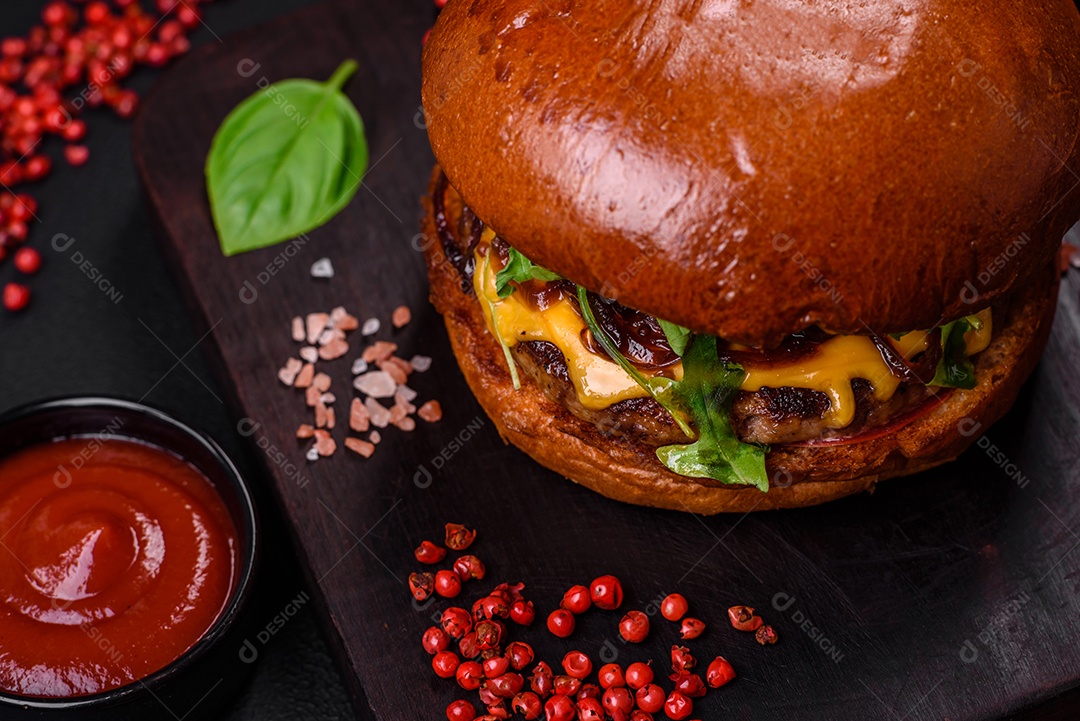 Hambúrguer com suculenta costeleta de carne, queijo, tomate, sal, especiarias e ervas sobre um fundo escuro de concreto