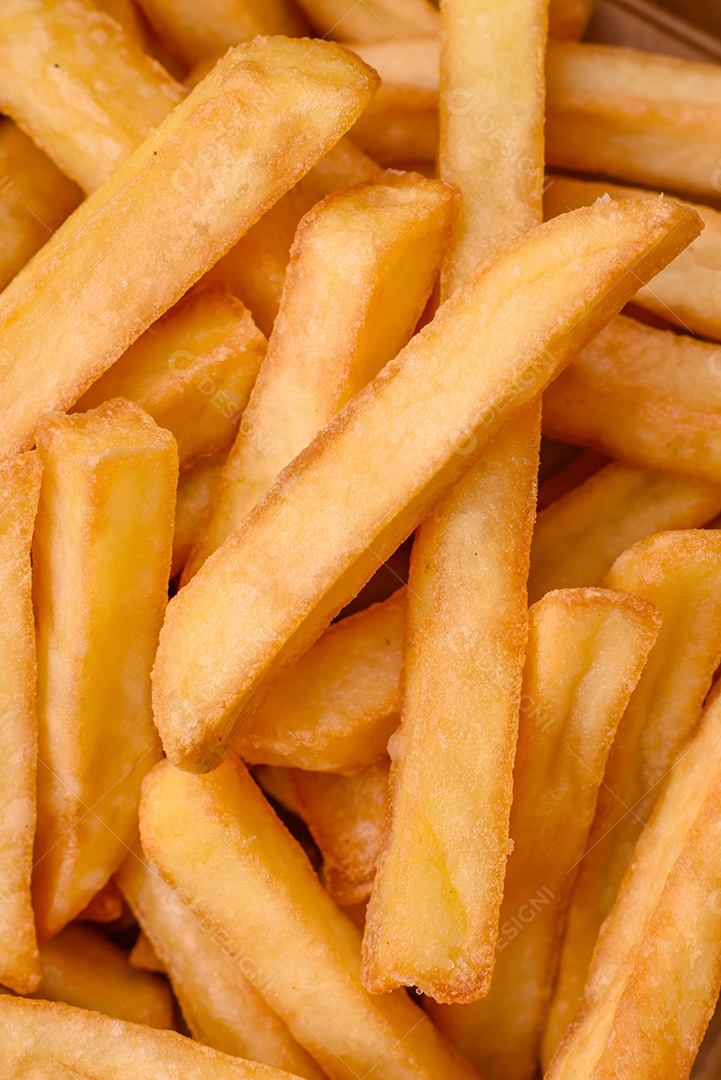 Deliciosas batatas fritas crocantes com sal e especiarias em uma caixa de papelão sobre um fundo escuro de concreto