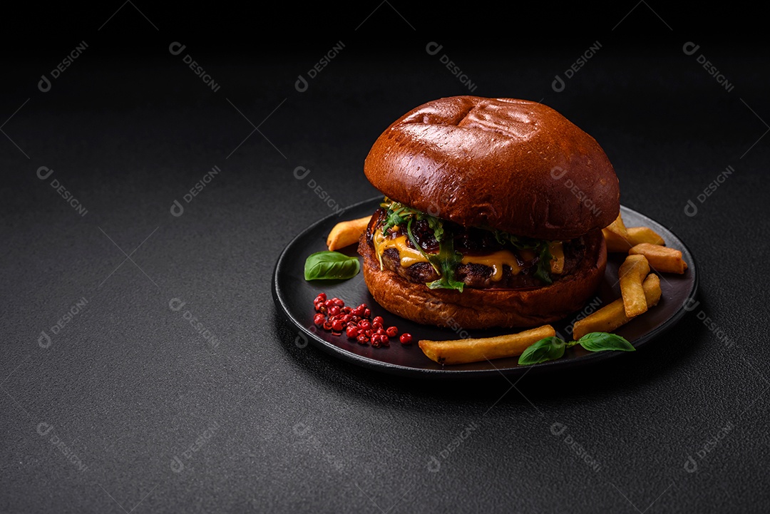 Hambúrguer com suculenta costeleta de carne, queijo, tomate, sal, especiarias e ervas sobre um fundo escuro de concreto