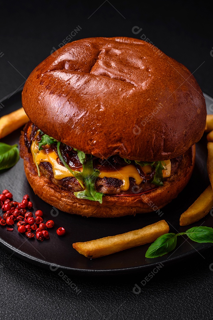 Hambúrguer com suculenta costeleta de carne, queijo, tomate, sal, especiarias e ervas sobre um fundo escuro de concreto