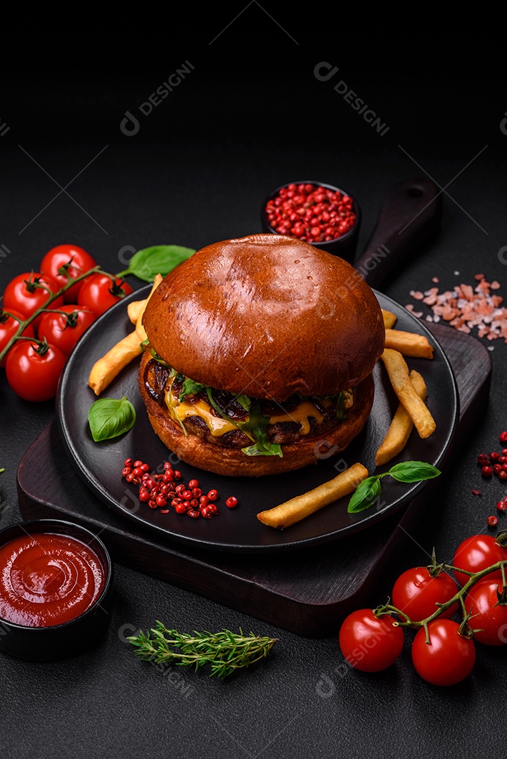 Hambúrguer com suculenta costeleta de carne, queijo, tomate, sal, especiarias e ervas sobre um fundo escuro de concreto