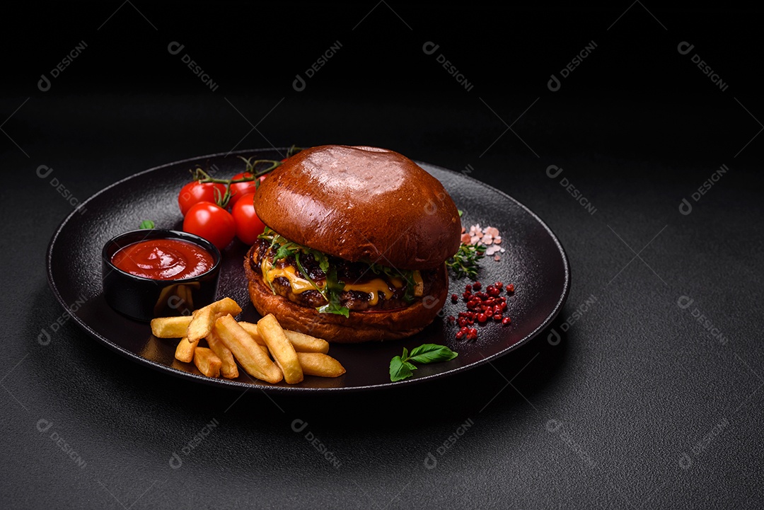 Hambúrguer com suculenta costeleta de carne, queijo, tomate, sal, especiarias e ervas sobre um fundo escuro de concreto