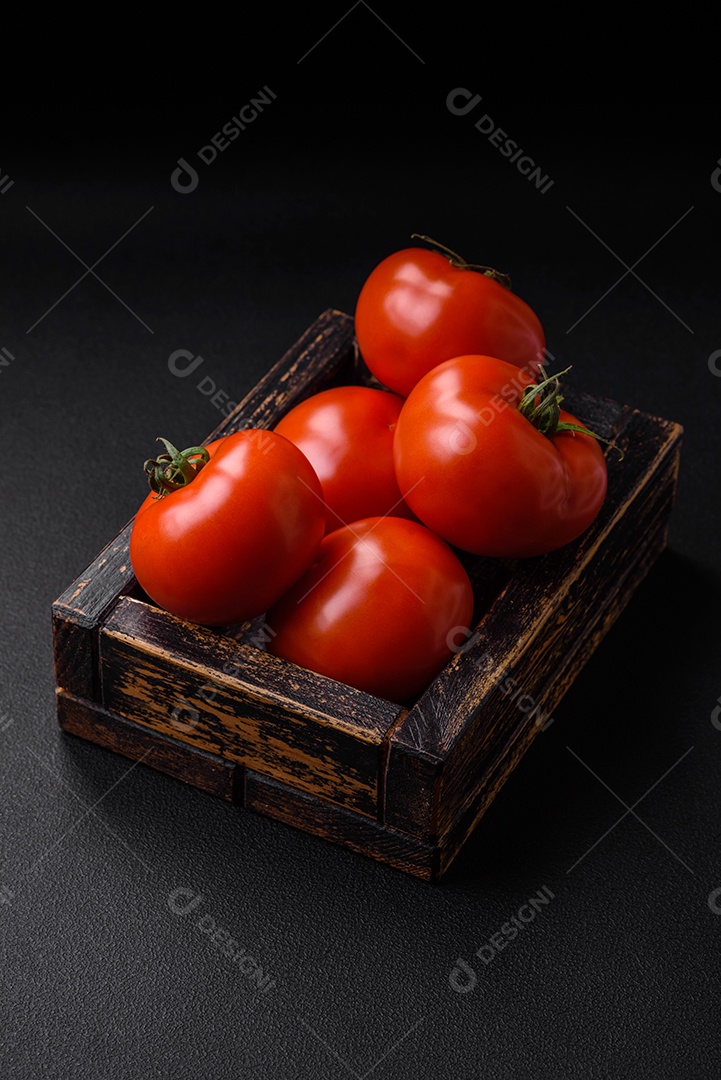 Deliciosos tomates suculentos frescos em um fundo escuro de concreto. Ingredientes do molho