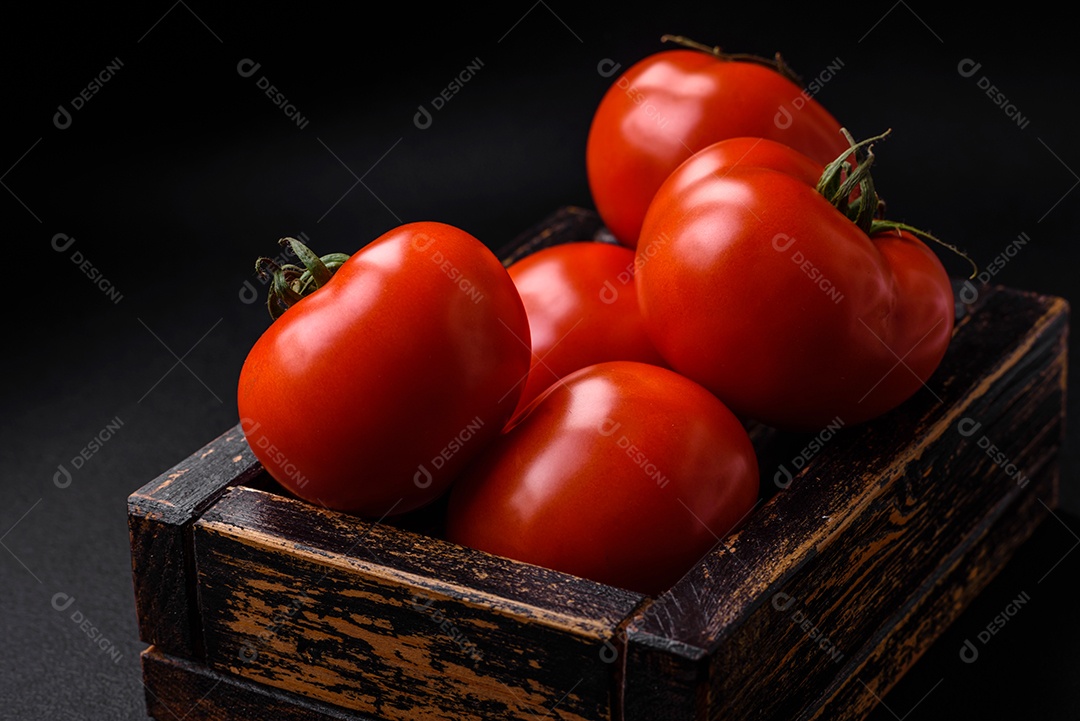 Deliciosos tomates suculentos frescos em um fundo escuro de concreto. Ingredientes do molho