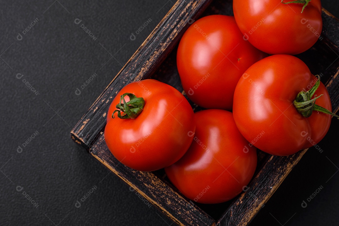 Deliciosos tomates suculentos frescos em um fundo escuro de concreto. Ingredientes do molho