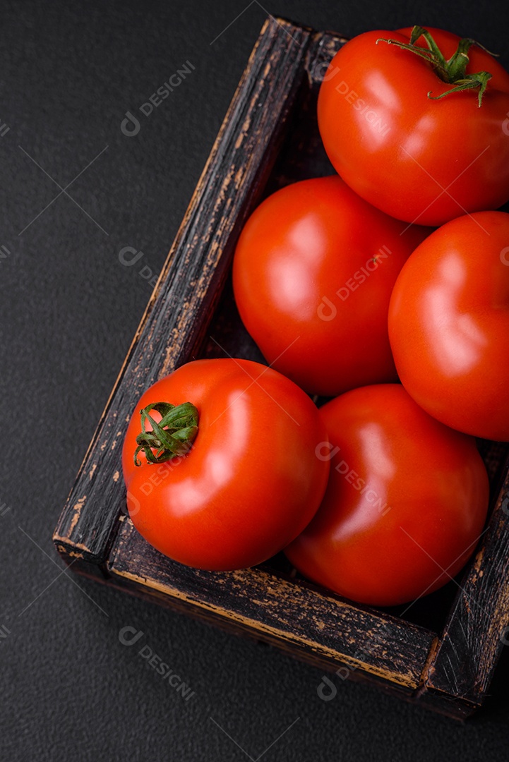 Deliciosos tomates suculentos frescos em um fundo escuro de concreto. Ingredientes do molho