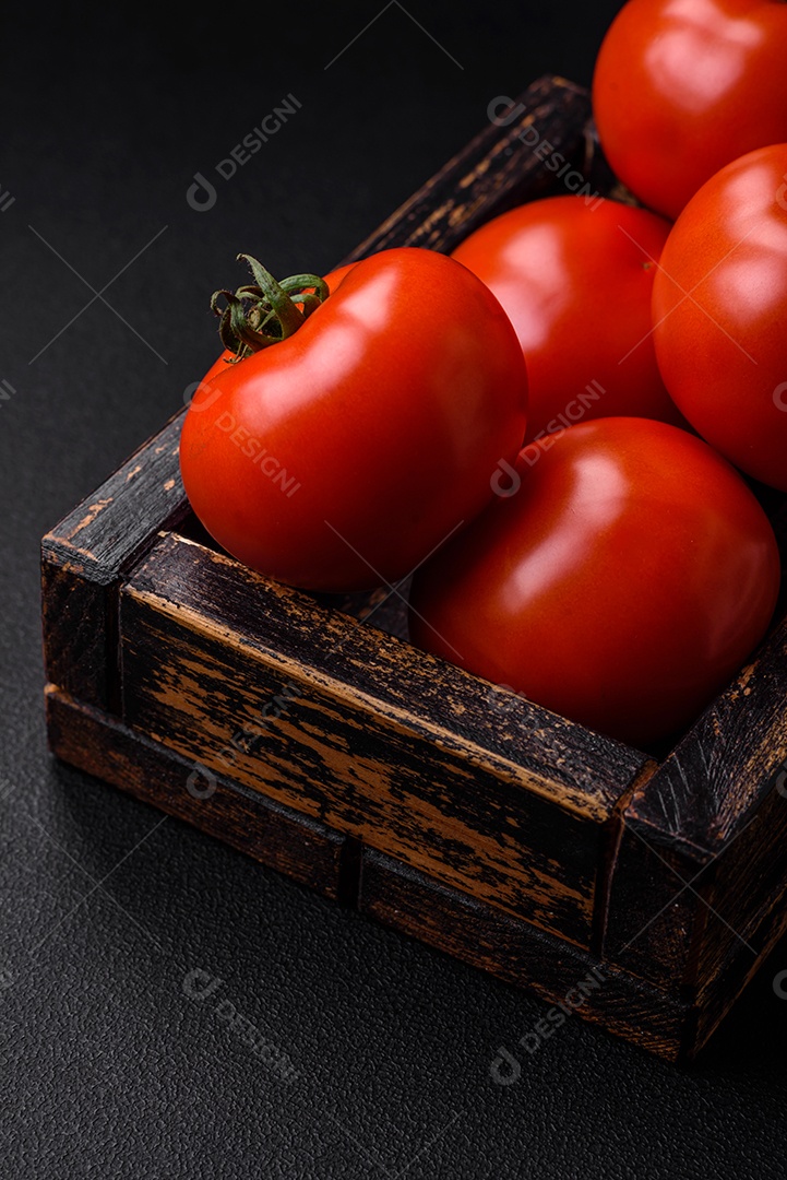 Deliciosos tomates suculentos frescos em um fundo escuro de concreto. Ingredientes do molho