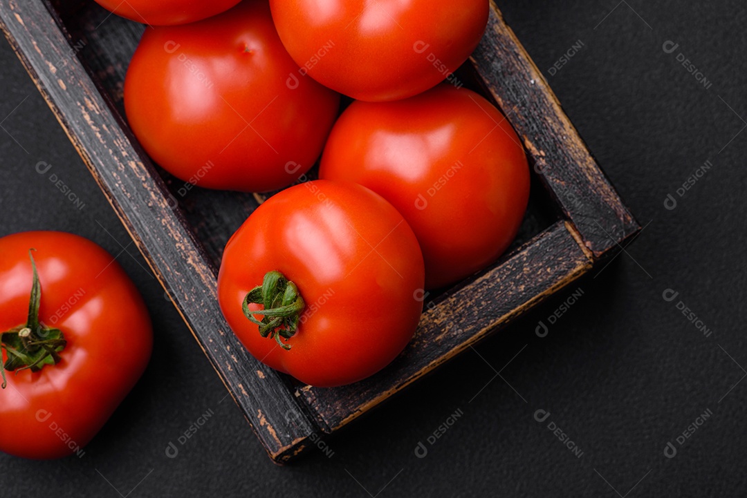 Deliciosos tomates suculentos frescos em um fundo escuro de concreto. Ingredientes do molho