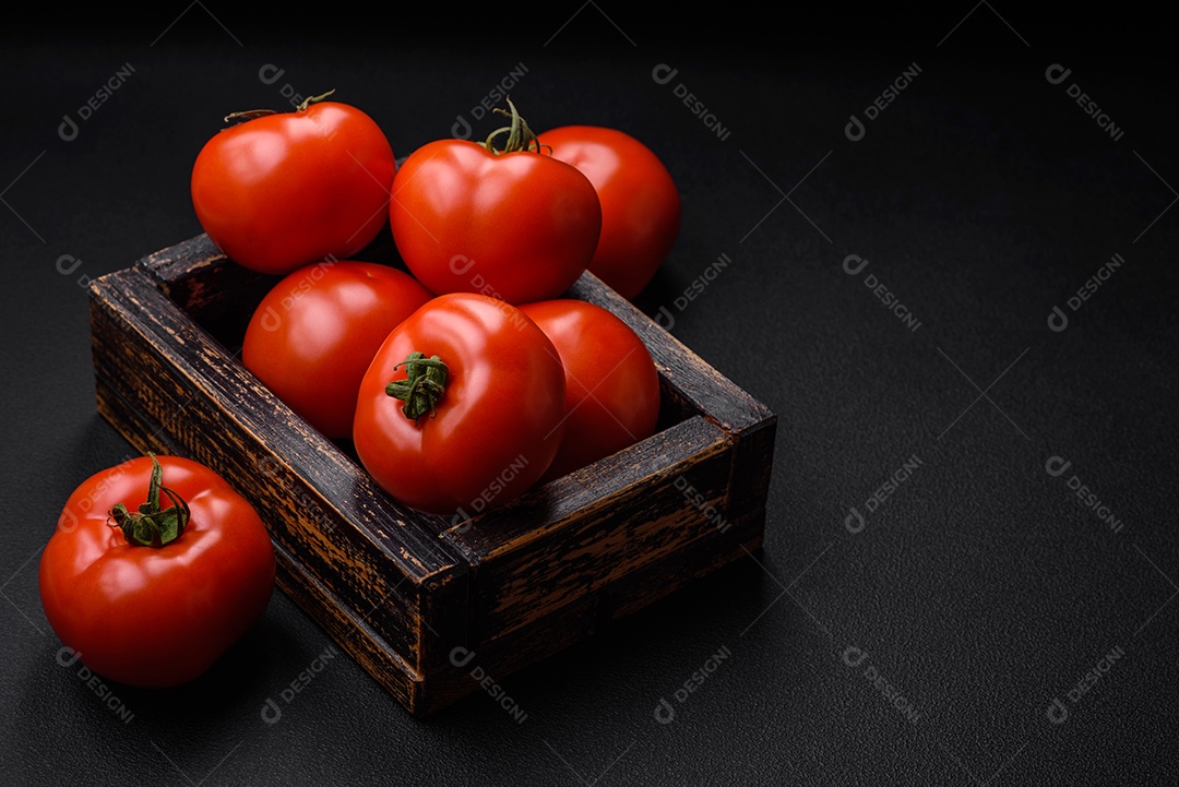 Deliciosos tomates suculentos frescos em um fundo escuro de concreto. Ingredientes do molho