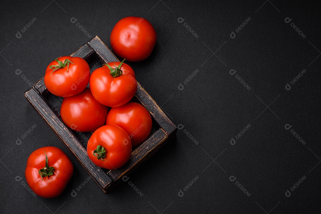 Deliciosos tomates suculentos frescos em um fundo escuro de concreto. Ingredientes do molho