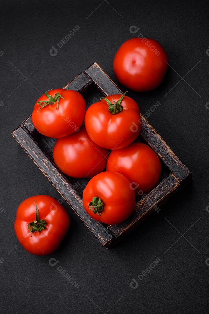 Deliciosos tomates suculentos frescos em um fundo escuro de concreto. Ingredientes do molho
