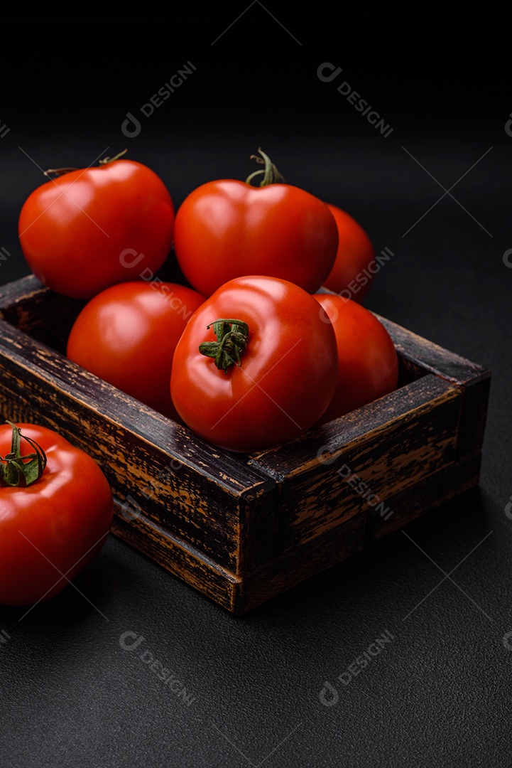 Deliciosos tomates suculentos frescos em um fundo escuro de concreto. Ingredientes do molho