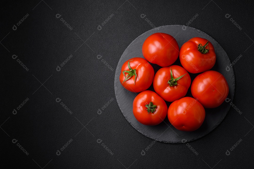 Deliciosos tomates suculentos frescos em um fundo escuro de concreto. Ingredientes do molho