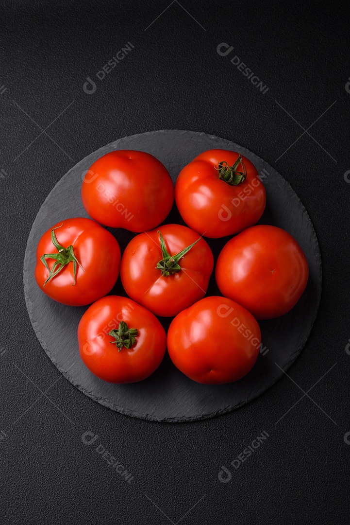 Deliciosos tomates suculentos frescos em um fundo escuro de concreto. Ingredientes do molho