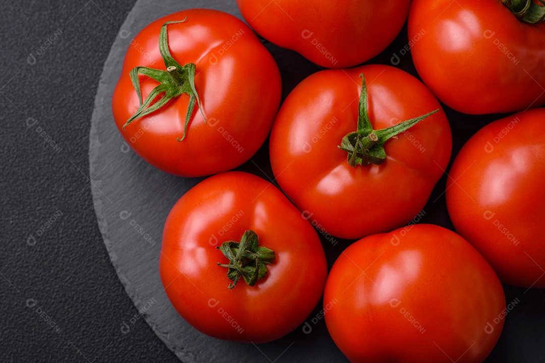 Deliciosos tomates suculentos frescos em um fundo escuro de concreto. Ingredientes do molho