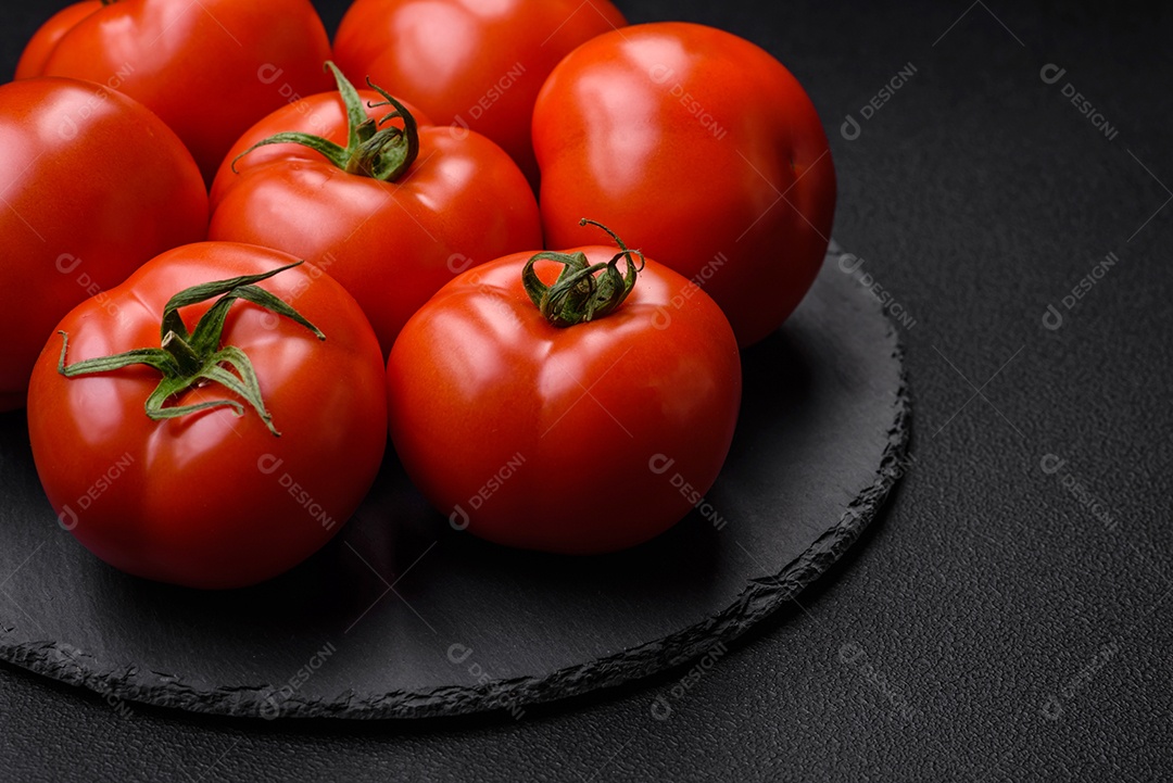 Deliciosos tomates suculentos frescos em um fundo escuro de concreto. Ingredientes do molho