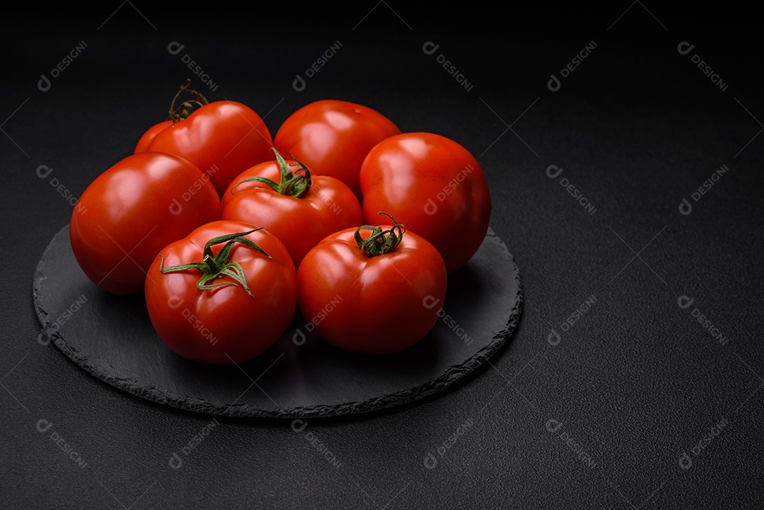 Deliciosos tomates suculentos frescos em um fundo escuro de concreto. Ingredientes do molho