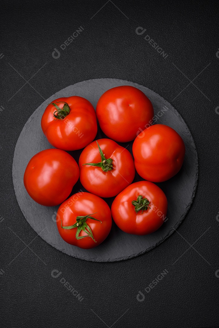 Deliciosos tomates suculentos frescos em um fundo escuro de concreto. Ingredientes do molho