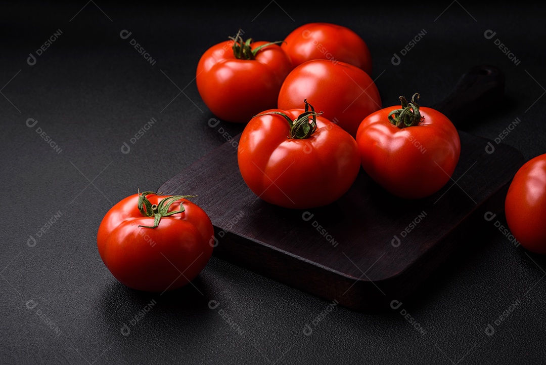 Deliciosos tomates suculentos frescos em um fundo escuro de concreto. Ingredientes do molho