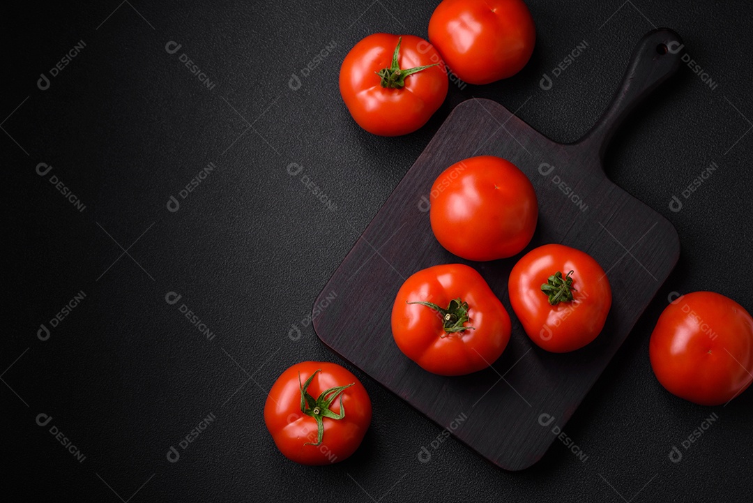 Deliciosos tomates suculentos frescos em um fundo escuro de concreto. Ingredientes do molho