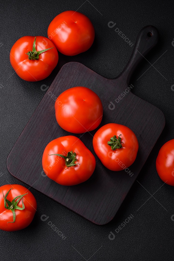 Deliciosos tomates suculentos frescos em um fundo escuro de concreto. Ingredientes do molho