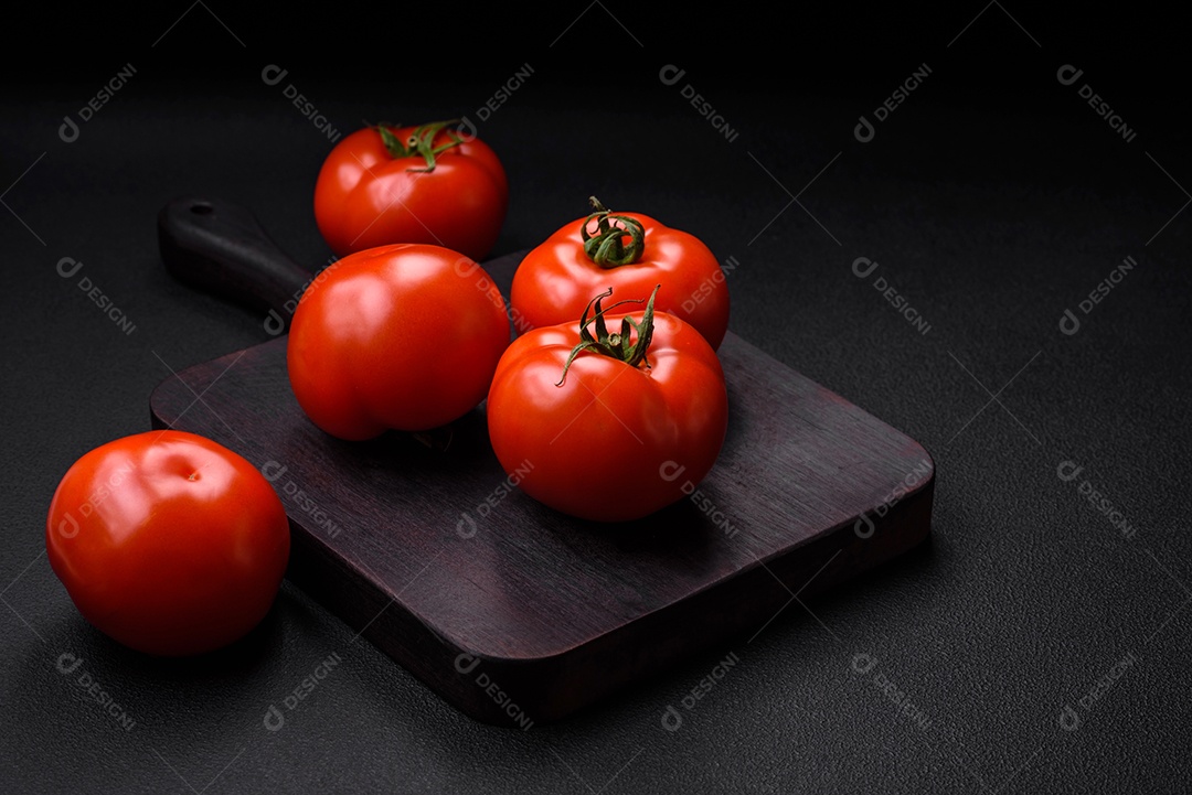 Deliciosos tomates suculentos frescos em um fundo escuro de concreto. Ingredientes do molho