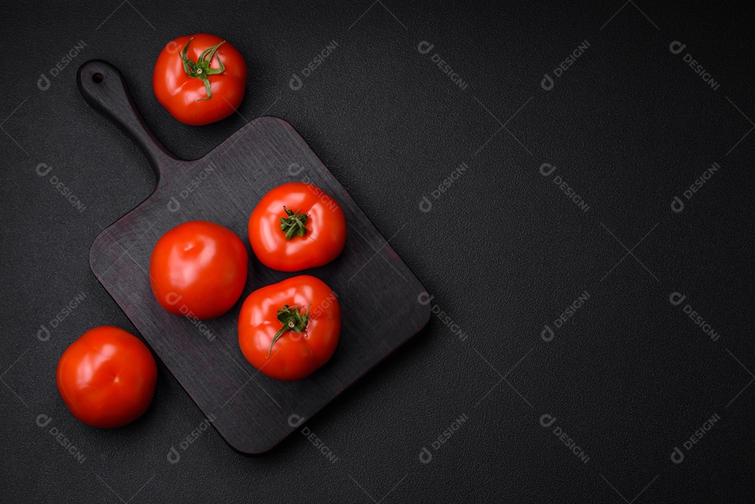 Deliciosos tomates suculentos frescos em um fundo escuro de concreto. Ingredientes do molho