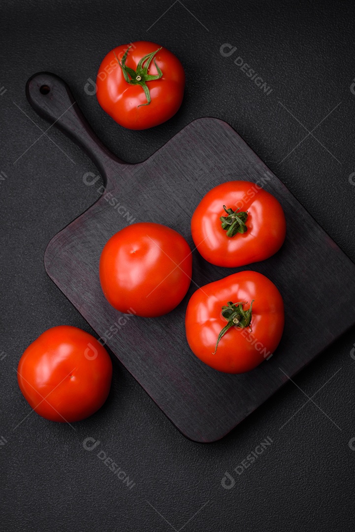 Deliciosos tomates suculentos frescos em um fundo escuro de concreto. Ingredientes do molho