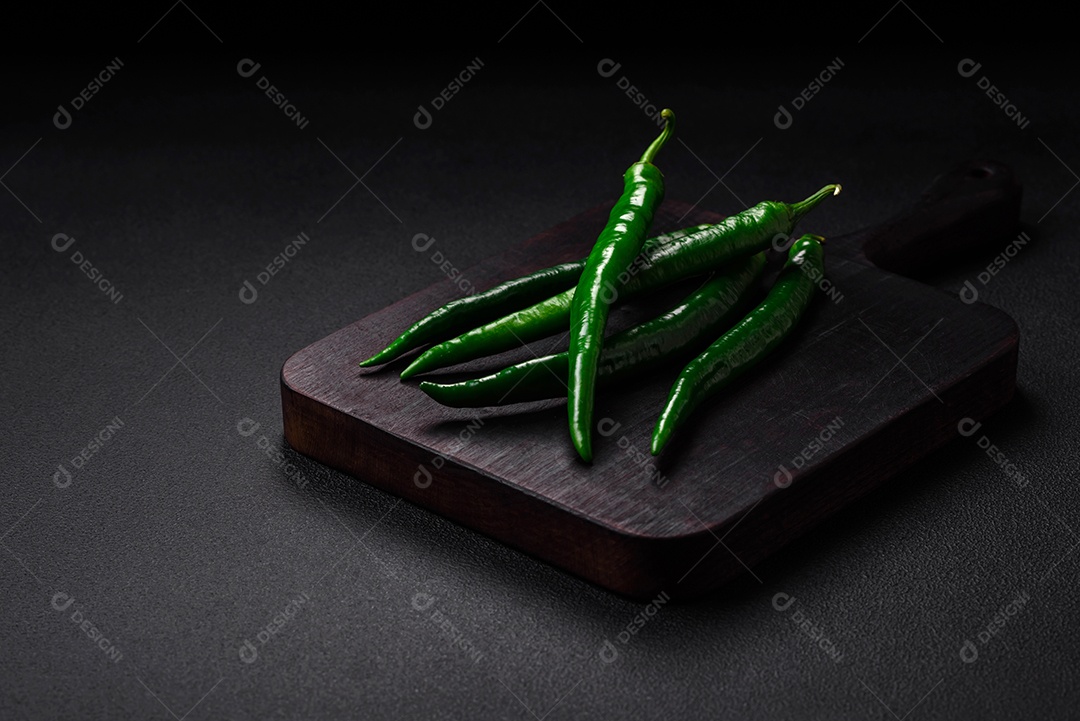 Pimentas verdes quentes frescas em um fundo escuro de concreto. Ingredientes para molho picante