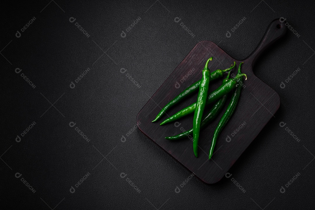 Pimentas verdes quentes frescas em um fundo escuro de concreto. Ingredientes para molho picante