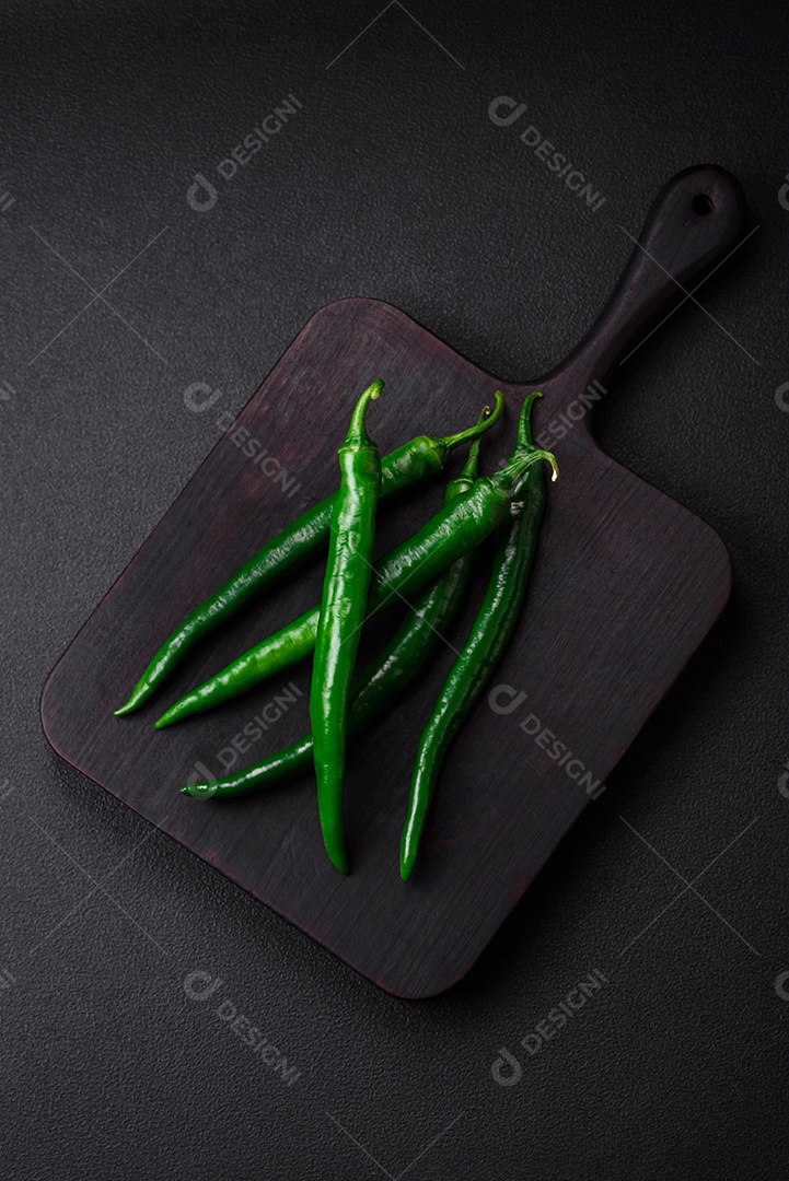 Pimentas verdes quentes frescas em um fundo escuro de concreto. Ingredientes para molho picante