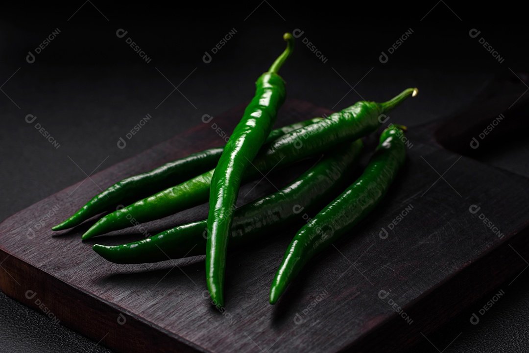 Pimentas verdes quentes frescas em um fundo escuro de concreto. Ingredientes para molho picante