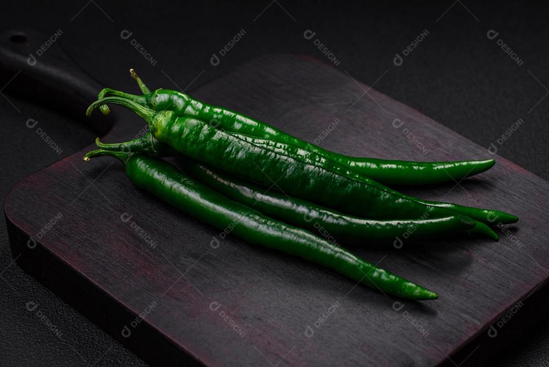 Pimentas verdes quentes frescas em um fundo escuro de concreto. Ingredientes para molho picante