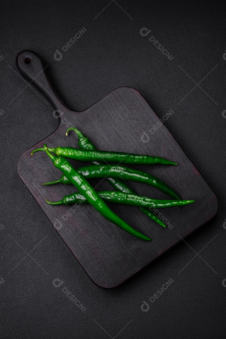 Pimentas verdes quentes frescas em um fundo escuro de concreto. Ingredientes para molho picante