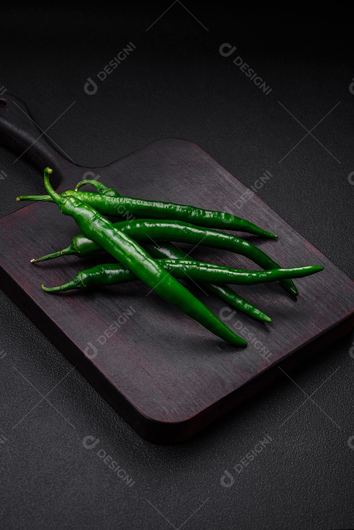 Pimentas verdes quentes frescas em um fundo escuro de concreto. Ingredientes para molho picante