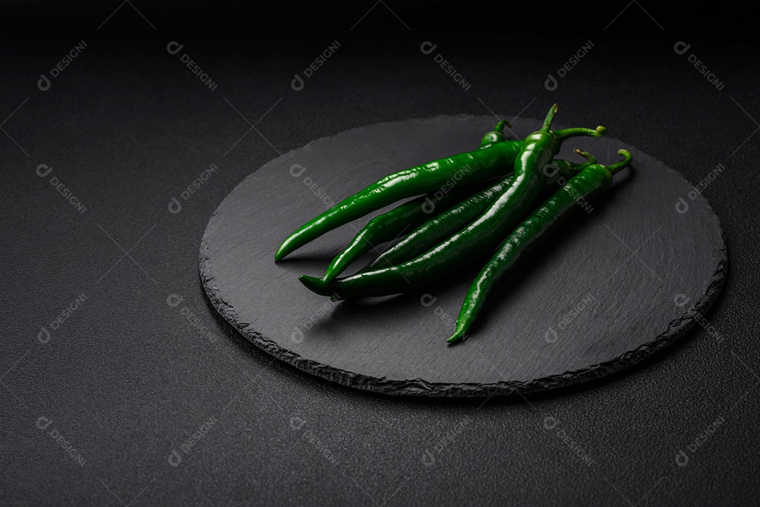 Pimentas verdes quentes frescas em um fundo escuro de concreto. Ingredientes para molho picante