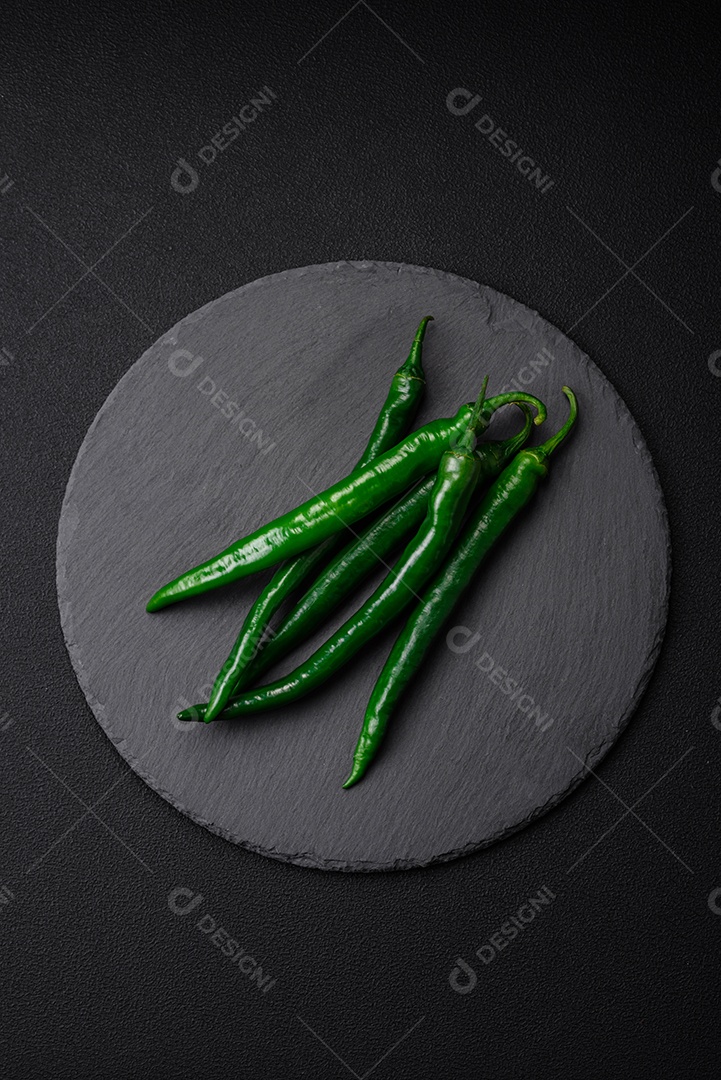 Pimentas verdes quentes frescas em um fundo escuro de concreto. Ingredientes para molho picante