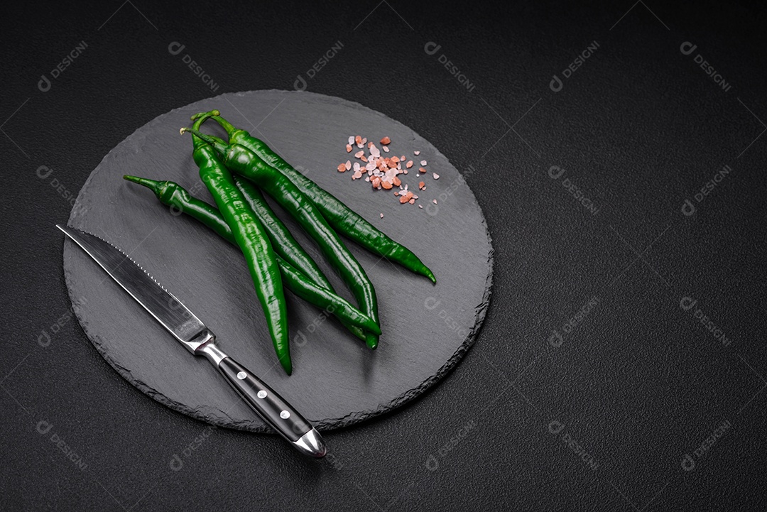 Pimentas verdes quentes frescas em um fundo escuro de concreto. Ingredientes para molho picante
